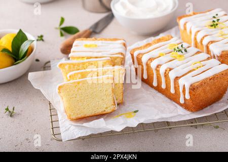 Classic lemon pound cake with powdered sugar glaze sliced on parchment paper topped with lemon zest Stock Photo