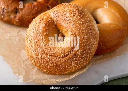 Homemade freshly baked bagels on a parchment paper ready to eat, cinnamon raisin, sesame and plain bagel Stock Photo