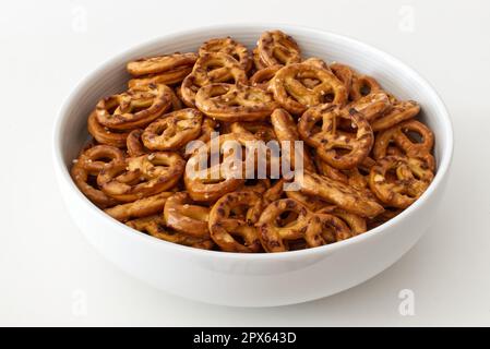 Salted savory mini pretzels in a bowl isolated on white background Stock Photo