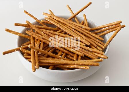 Salted pretzel sticks in a bowl isolated on white background Stock Photo