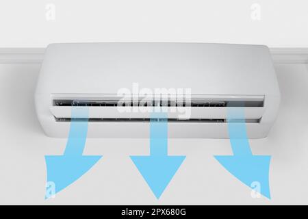 Fresh cool air flow, shown by blue arrows, from a white wall-mounted air conditioner Stock Photo