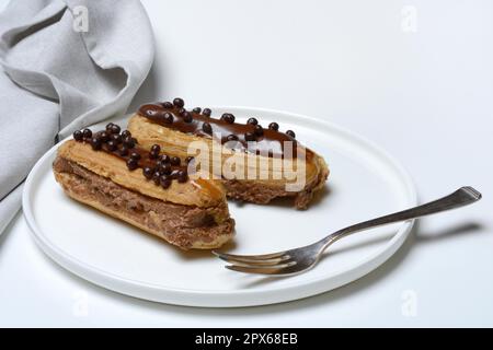 Two chocolate eclairs on a plate, eclair Stock Photo