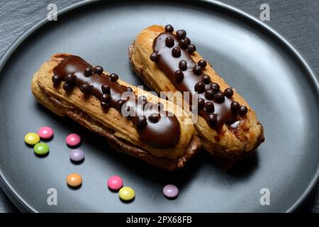 Two chocolate eclairs on a plate, eclair Stock Photo