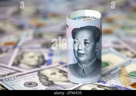 Chinese yuan banknote rolled up on US dollars background. Concept of trade war between the China and USA, economic, sanctions and investment Stock Photo