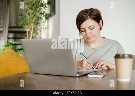 Close up smiling woman work at laptop. Looking at laptop screen, reading good news in message, speak phone, chatting enjoying leisure time with comput Stock Photo