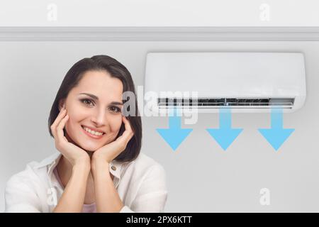 Portrait of a smiling happy woman in a bright fresh room with the air conditioner turned on Stock Photo