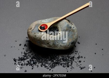 Black Hawaiian salt on spoons and in hollowed stone, sea salt with activated charcoal Stock Photo