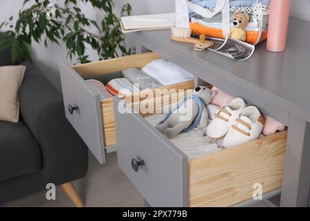 Open drawers of chest with baby stuff in room Stock Photo