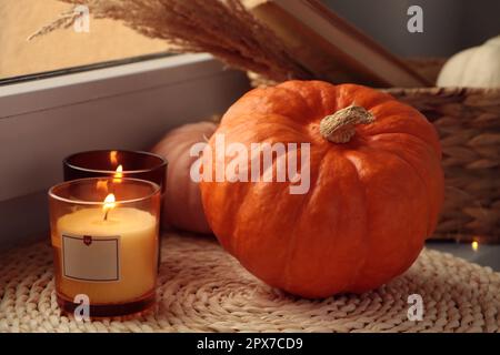 Scented candles and pumpkins on window sill indoors Stock Photo