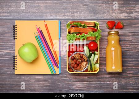 Lunch box with healthy food for schoolchild and different stationery on wooden table, flat lay Stock Photo