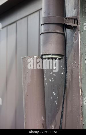 Down pipe / downpipe drain that's broken apart on apartment block and releasing water which can then cause damp / drips / water leak. UK. (134) Stock Photo