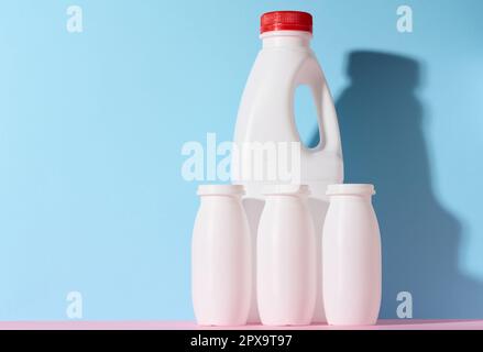 White plastic bottles for yogurt and dairy products on a blue background Stock Photo