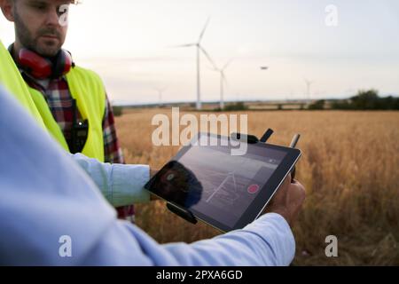 Close up of operator hands holding remote control and quad copter. Engineers controlling data dron. Stock Photo