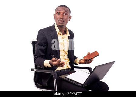 portrait of a confused businessman sitting on a chair with a computer on his legs and gesturing with his hands. Stock Photo