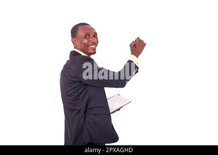 smiling portrait of young teacher holding notebook and writing on whiteboard with pen. Stock Photo