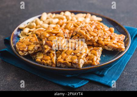 Sweet peanut brittle. Tasty peanuts in caramel on the plate. Stock Photo