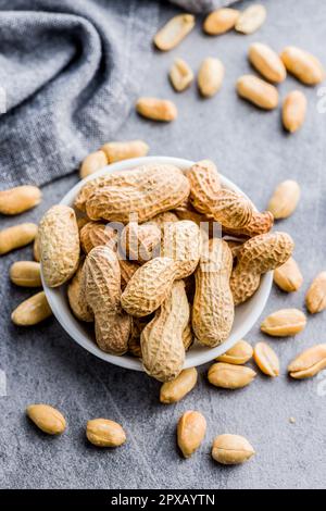 Unpeeled and peeled peanuts on the kitchen table. Stock Photo