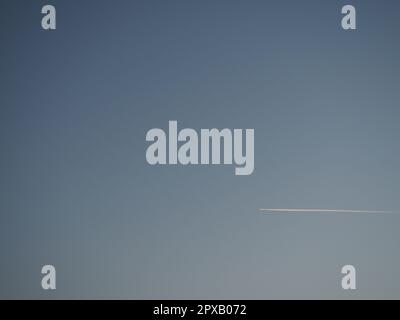 plane and trail in the evening sky blue. Abstract background on a space or aero theme. Color gradient. Stock Photo