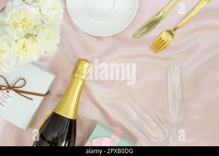 Festive table set concept, Champagne with glass and peony with gift box on table cloth for diner. Stock Photo