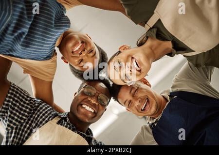 portrait of happy designers from below. group of fashion designers huddled together. Colleagues collaborating at work. Young tailors working in their Stock Photo