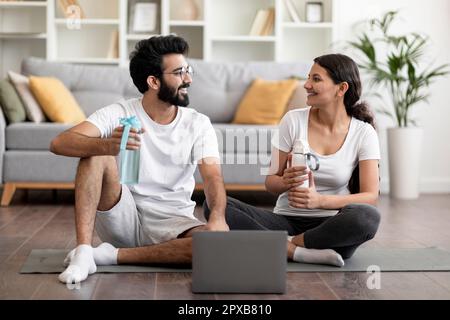 Young indian couple having break while exercising together with laptop at home Stock Photo