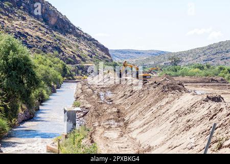 Boegoeberg Dam, South Africa - Feb 28 2023: Backhoe loaders clearing sand that blocked the irrigation canal at Boegoeberg Dam Stock Photo