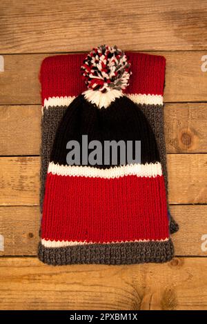 Handmade wool knitted winter red and black hat and scarf isolated on old wood background Stock Photo