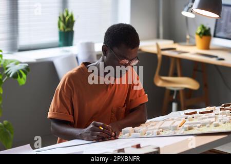 African American architect in eyeglasses concentrating on his work over new plan of construction Stock Photo