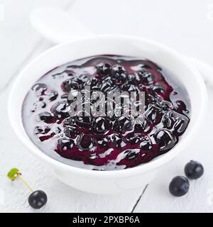 Fresh homemade jam made of Patagonian Calafate berries (lat. Berberis heterophylla), served in white bowl (Selective Focus, Focus one third into the j Stock Photo