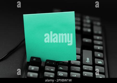 Colored sticker lying on keyboard. Important message written over paper. Stock Photo