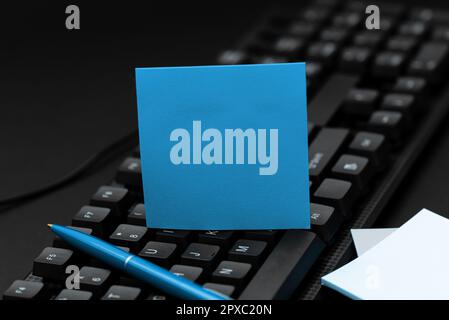 Sticker lying on black keyboard. Important message written over paper. Stock Photo