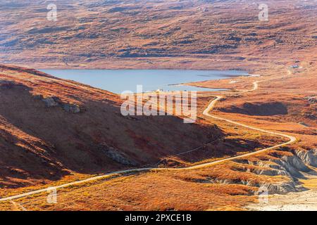 Autumn greenlandic orange tundra landscape with road to the lake and mountains in the background, Kangerlussuaq, Greenland Stock Photo