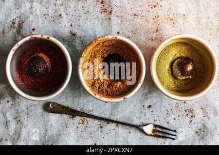 Chickpea truffles with dried fruit being coated in different types of powder Stock Photo