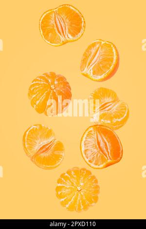 Isolated flying grapes. Seven whole and sliced mandarin fruits falling on yellow background with clipping path as package design element and advertisi Stock Photo