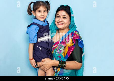 Young happy indian mother with her cute little girl wearing school uniform. Rural india, Education concept. Stock Photo