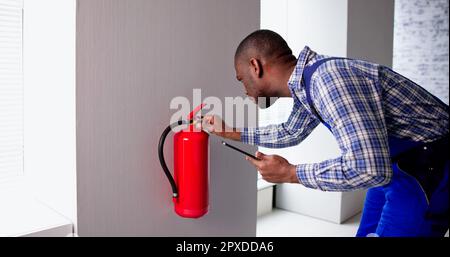 Male Professional Checking A Fire Extinguisher. Security Inspection Stock Photo