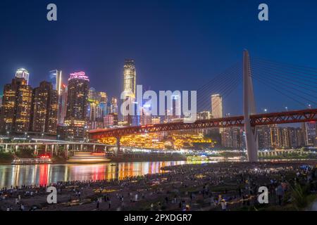 CHONGQING, CHINA - MAY 1, 2023 - Tourists enjoy the night view of Hongya Cave Scenic spot and mountain town on the riverbank opposite Hongyadong in Ch Stock Photo