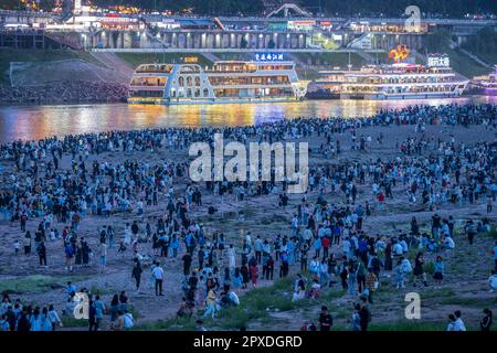 CHONGQING, CHINA - MAY 1, 2023 - Tourists enjoy the night view of Hongya Cave Scenic spot and mountain town on the riverbank opposite Hongyadong in Ch Stock Photo