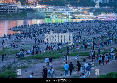 CHONGQING, CHINA - MAY 1, 2023 - Tourists enjoy the night view of Hongya Cave Scenic spot and mountain town on the riverbank opposite Hongyadong in Ch Stock Photo