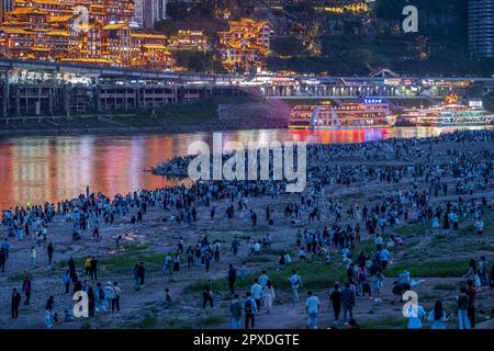 CHONGQING, CHINA - MAY 1, 2023 - Tourists enjoy the night view of Hongya Cave Scenic spot and mountain town on the riverbank opposite Hongyadong in Ch Stock Photo