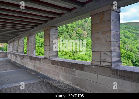 Columns on the pedestrian path on the Edersee dam in Germany with a view of the green forest Stock Photo