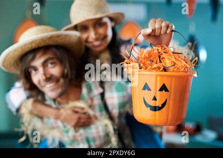 Its candy time. a young couple dressed in halloween costumes being being playful at home. Stock Photo