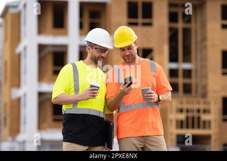 photo of engineer men using phone at construction site. engineer men at construction site. Stock Photo