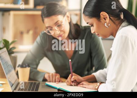 My team member keeps me sharp. two female businesswoman making notes in a notebook. Stock Photo