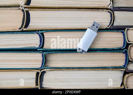 Computer usb drive on the background of a stack of old paper books. Information storage media. Top view with copy space Stock Photo