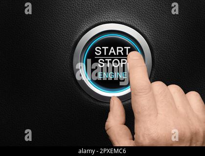 Finger about to press Engine start button with blue glowing ring in a modern car Stock Photo