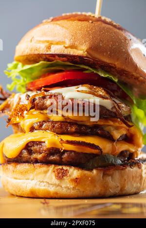 Loaded cheeseburgers three triple, stacked patties stacked high with layers of cheese, lettuce, and tomato. Tall cheeseburger Stock Photo