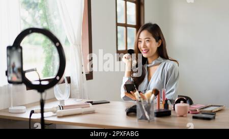Beauty blogger using brush with powder to applying product for reviewing cosmetic in makeup vlogger. Stock Photo