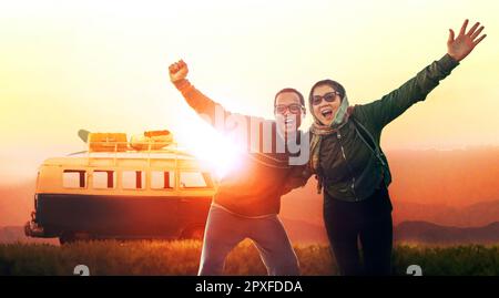 asian couples happiness acting at open field with camping car against beautiful sunset Stock Photo