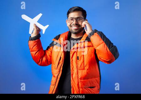 Passenger, journey, vacation. One young man clutching paper cut airplane and making phone call. Stock Photo